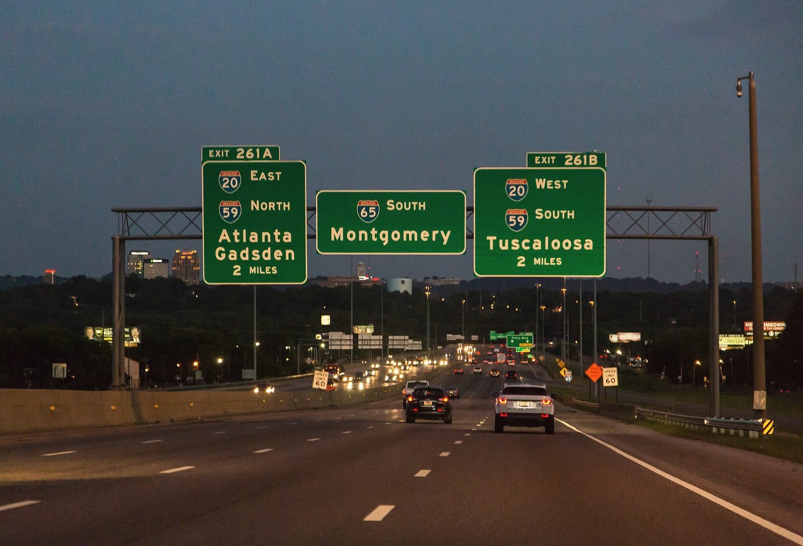 Green interstate signs for I-65 and I-20/59 over traffic at night in Birmingham