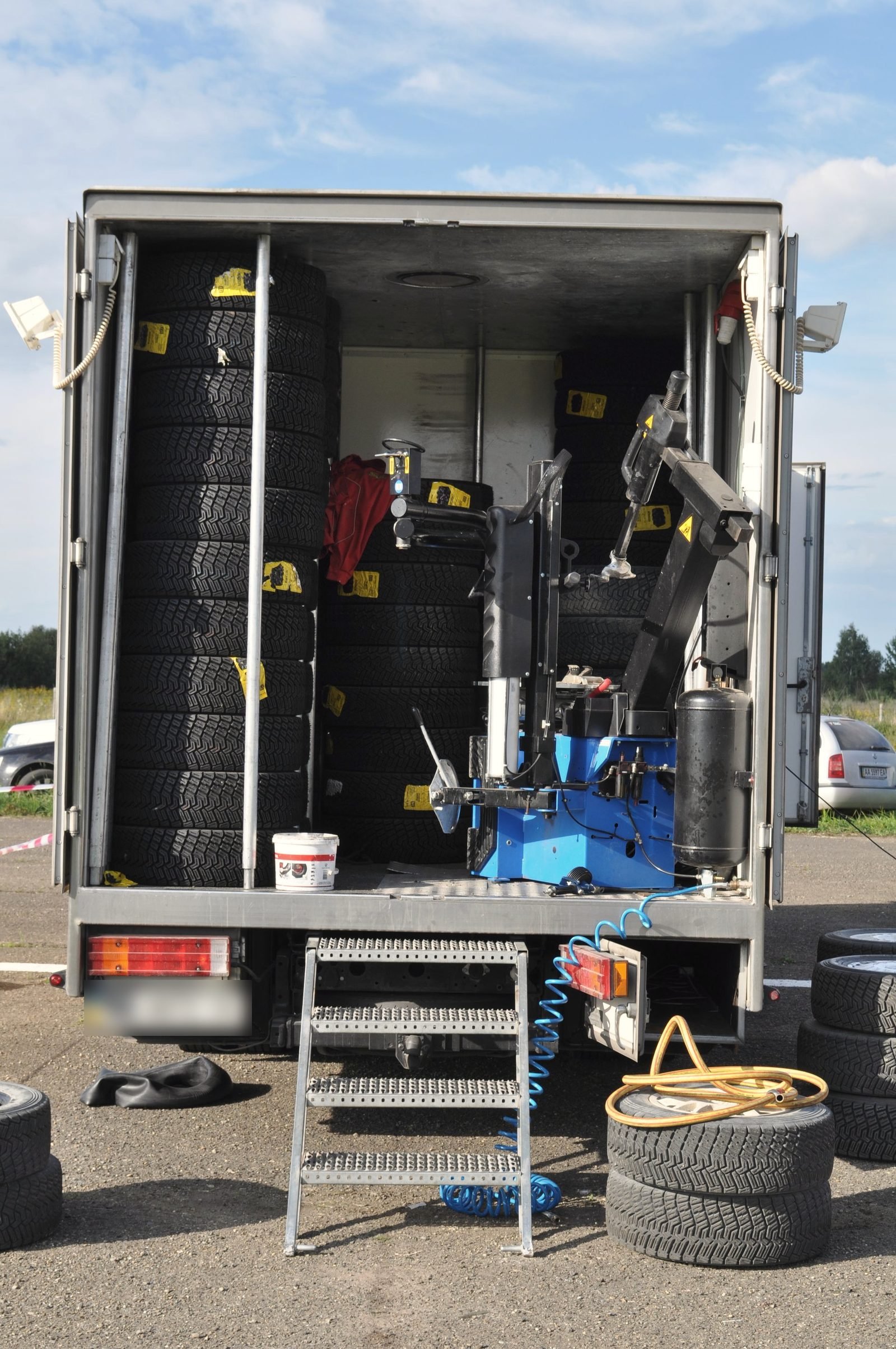 The open back of a tire service van stocked with tires and a tire machine
