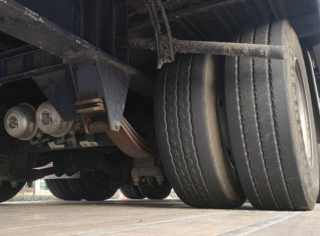 Looking up at the tandem axles, air bags and dual tires under a semi trailer